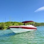 Lancha Real 220 Dóia navegando em Cabo Frio com grupo de passageiros a bordo.
