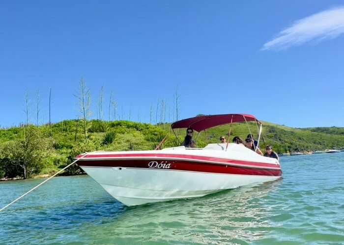 Lancha Real 220 Dóia navegando em Cabo Frio com grupo de passageiros a bordo.