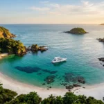 Praia paradisíaca em Búzios vista aérea com água cristalina turquesa e barco ancorado próximo a costão rochoso