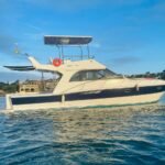 Lancha Carbrasmar ancorada em enseada, com casco azul e branco e flybridge coberto