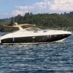 Lancha Real 45 fundeada em enseada de águas verdes, com bimini aberto e bote de apoio na popa